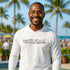 Man wearing a white 'Pickleball' shirt with palm trees and people in the background